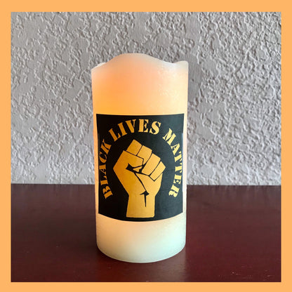 Black Lives Matter FistFlameless Real Wax - unscented Glowing Warm White LED candle. Dimensions: 3" D x 6" H (7.62 x 15.24 cm).